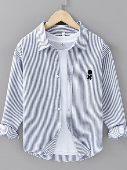 Striped shirt with a small black logo on a hanger against a gray background