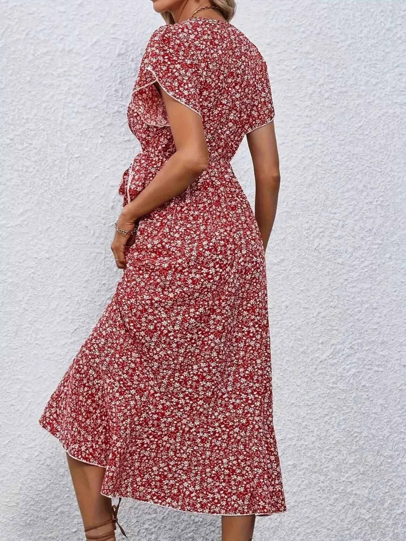 Red floral dress worn by a person against a white textured wall