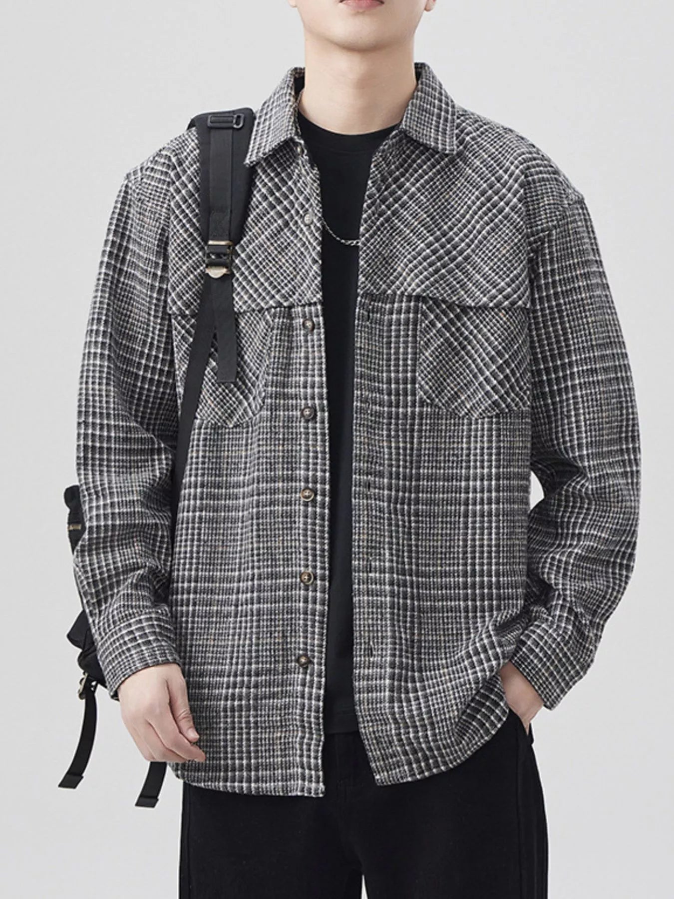 Person wearing a plaid shirt with a backpack on a plain background