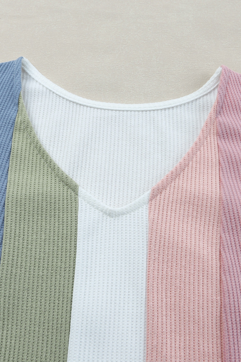 Color-blocked sweater with blue, green, white, and pink sections on a neutral background