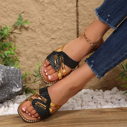 Black and gold sandals worn on a person's feet with a neutral background