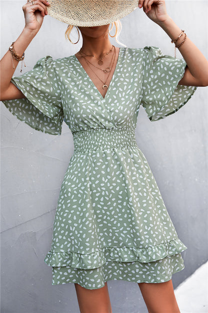 Woman wearing a green patterned dress against a gray background