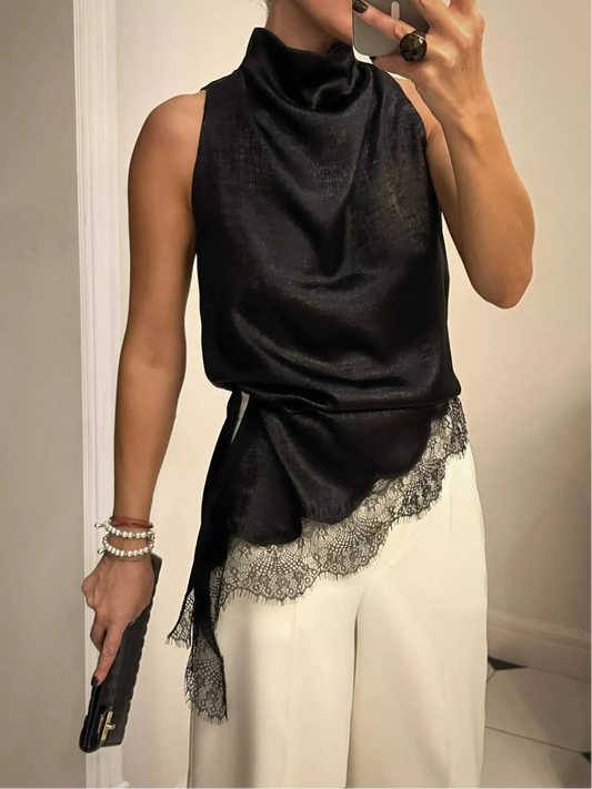 Person wearing a black sleeveless top with lace trim and white pants, taking a mirror selfie.