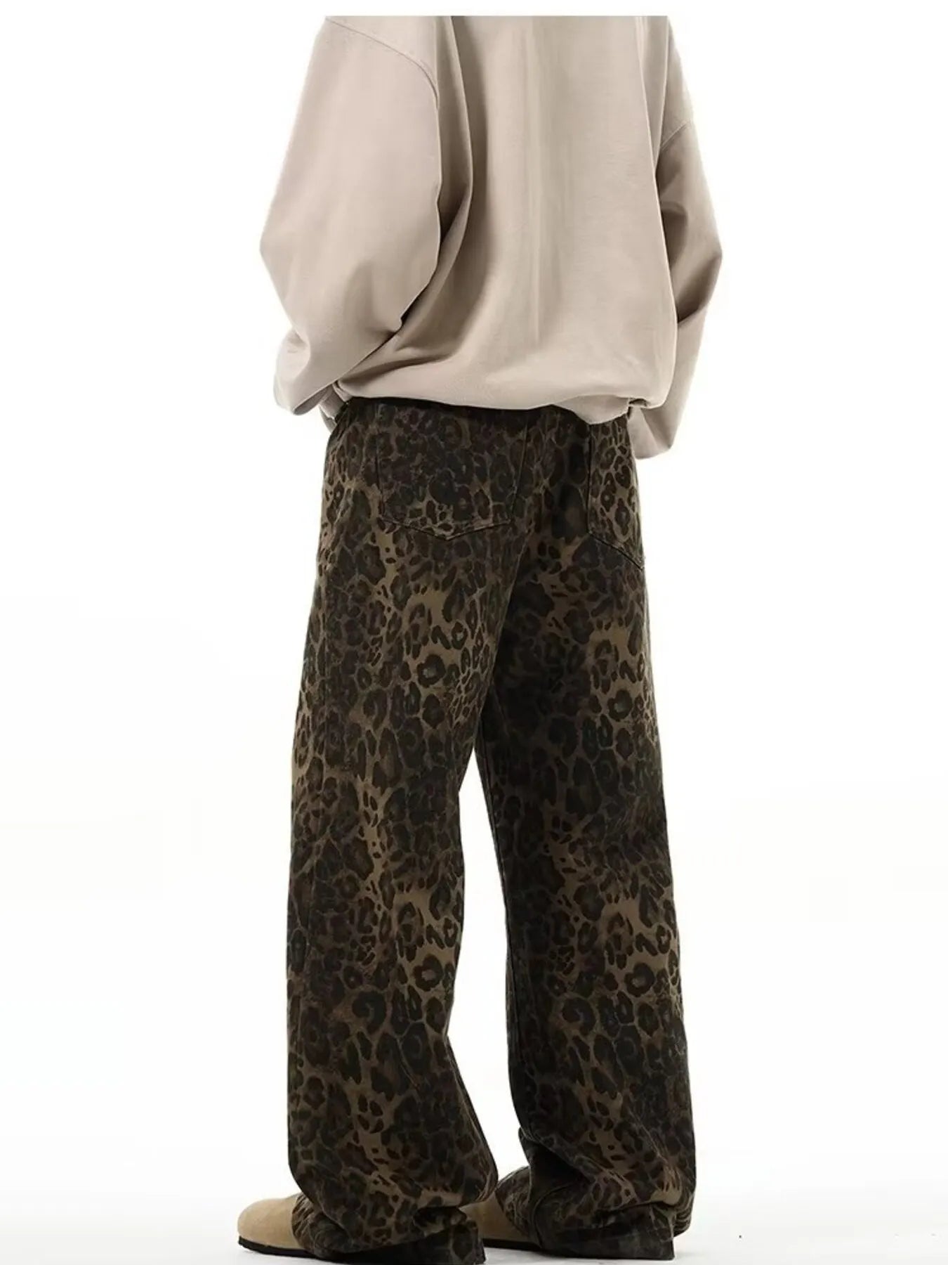 Person wearing leopard print pants and a beige sweatshirt on a white background