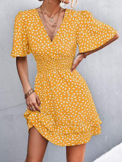 Woman wearing a yellow patterned dress against a gray background