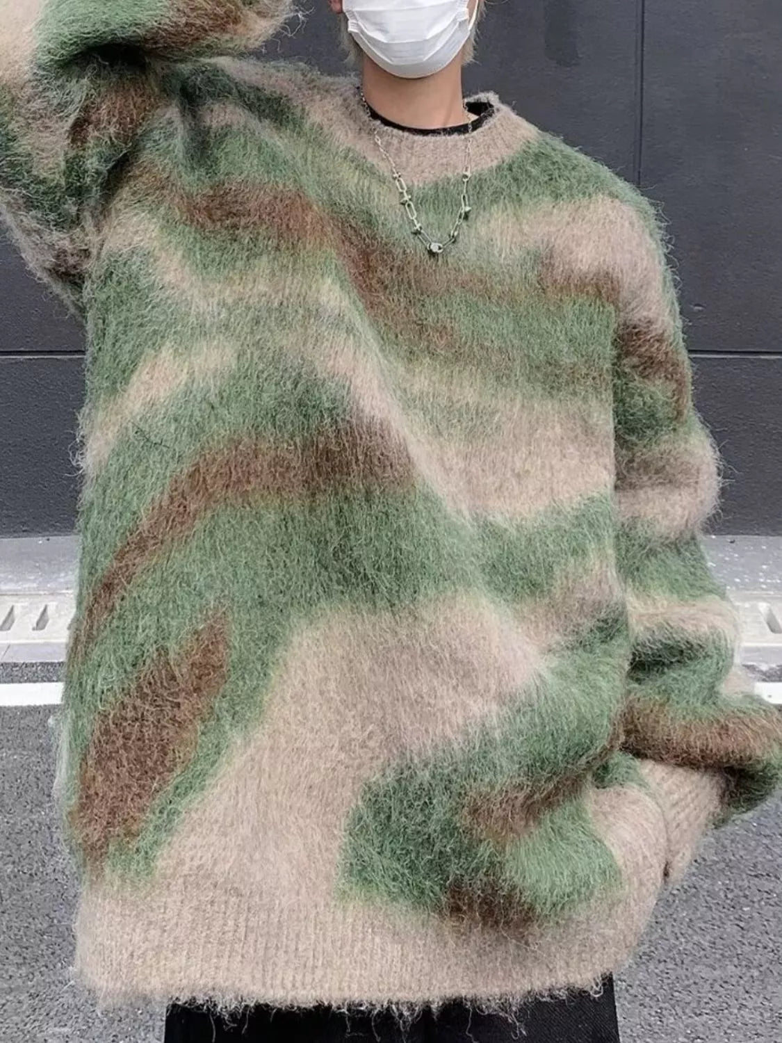 Person wearing a camouflage-patterned sweater with a neutral background