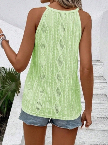 Person wearing a light green knitted tank top and denim shorts against a white wall.