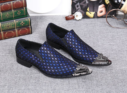 Blue patterned loafers with decorative metal accents on a gray surface.