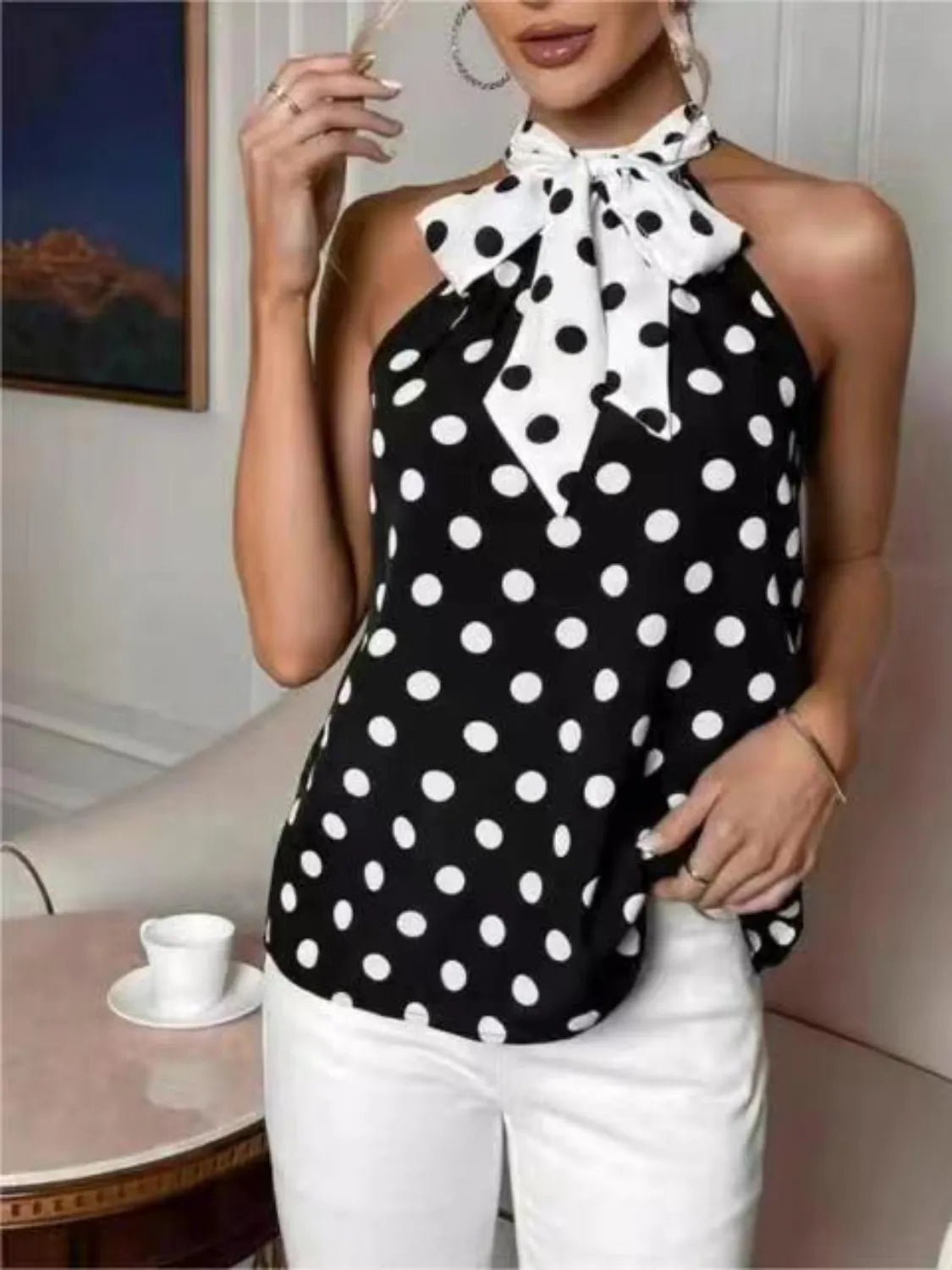 Woman wearing a black and white polka dot halter top in an indoor setting.