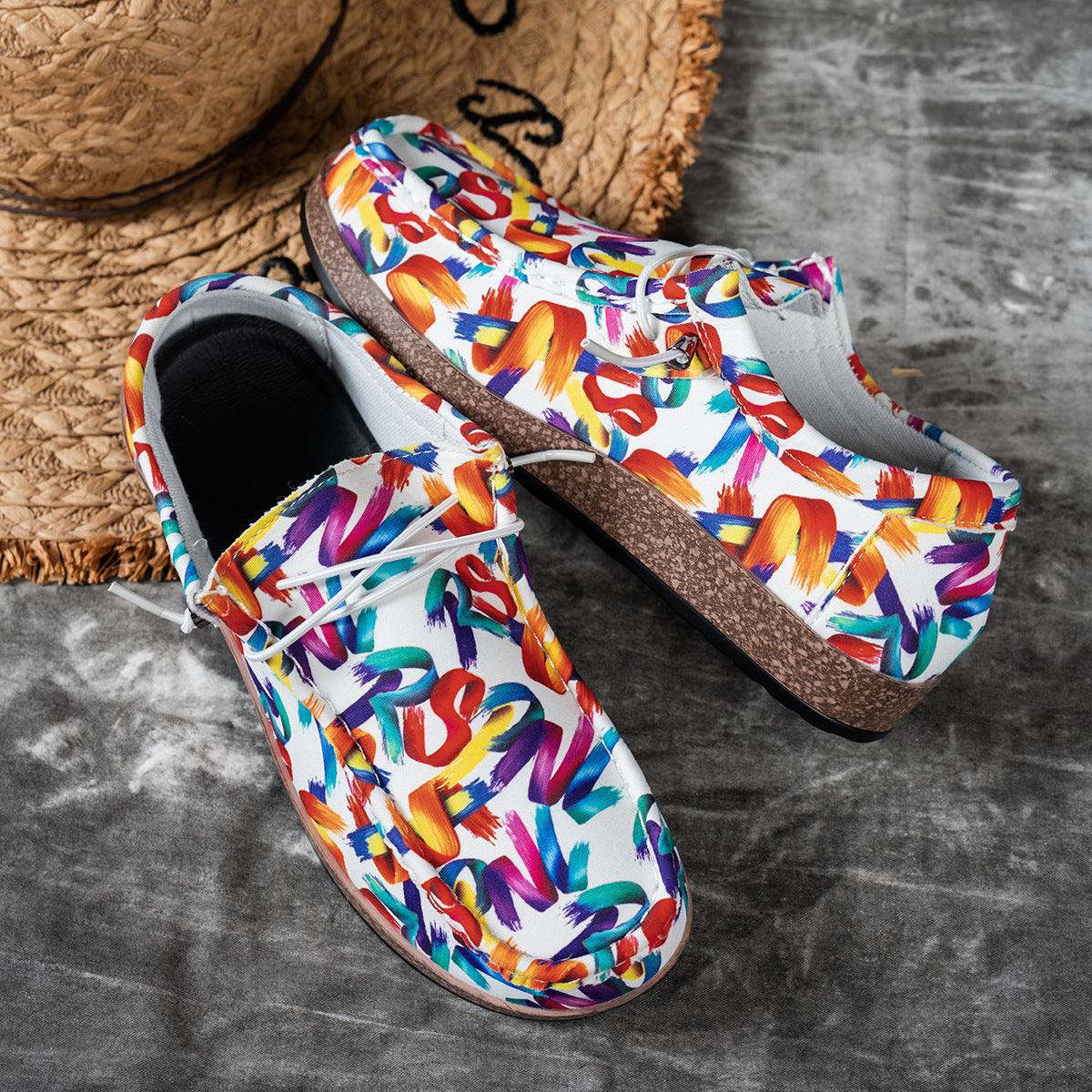 Colorful slip-on shoes with multicolor text design on a gray surface.