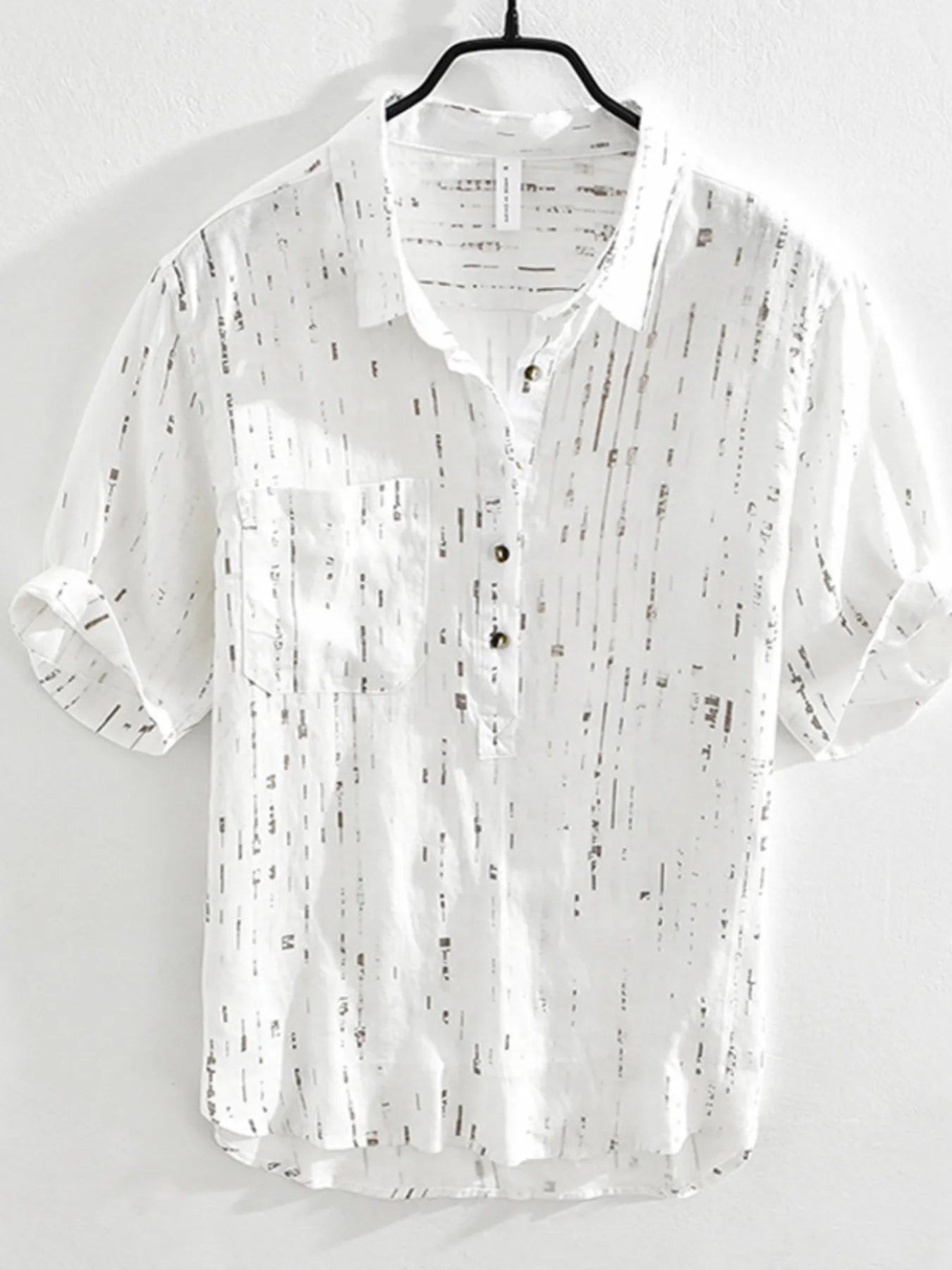 White shirt with black pattern on a hanger against a white background
