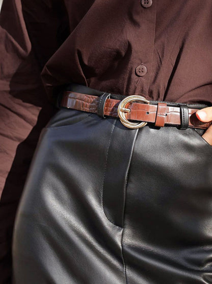 Person wearing a brown shirt and black leather pants with a brown belt.