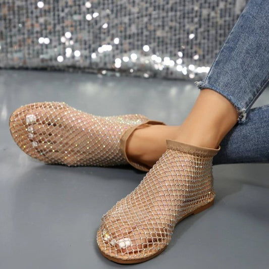 Brown mesh ankle boots worn with jeans on a gray surface.