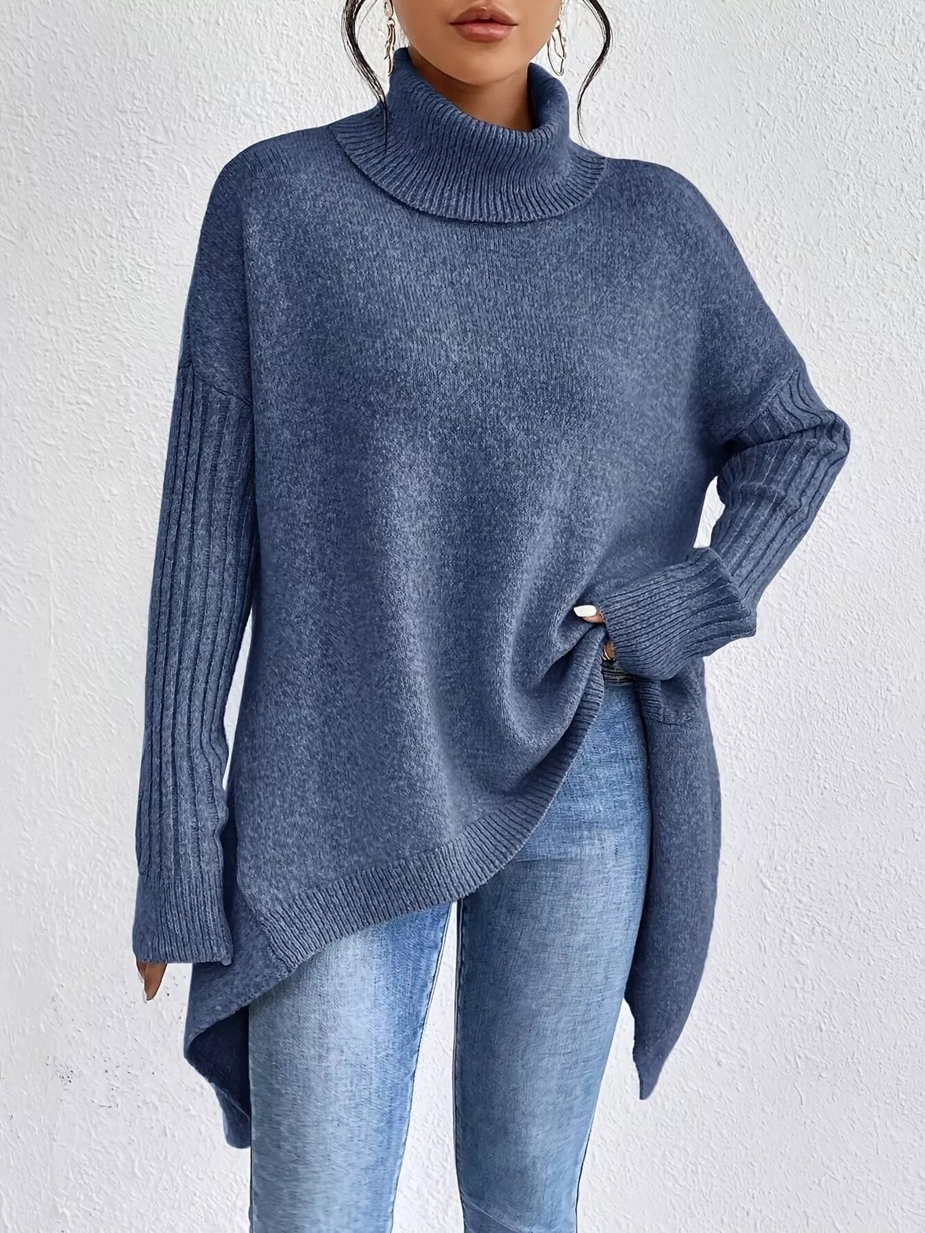 Person wearing a blue sweater and jeans against a white background