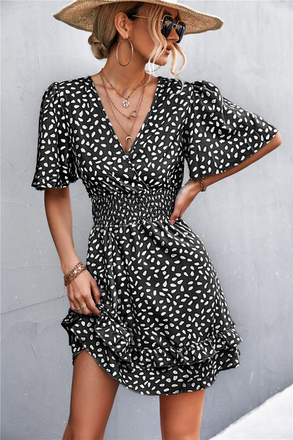 Woman wearing a black and white dot dress with a straw hat against a gray background