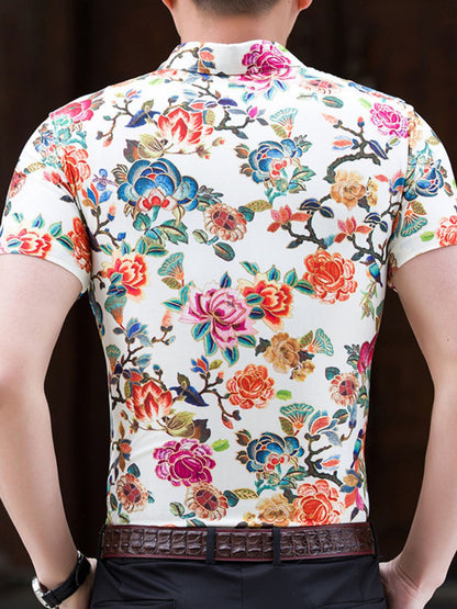 Person wearing a short-sleeve shirt with a colorful floral pattern on a dark background