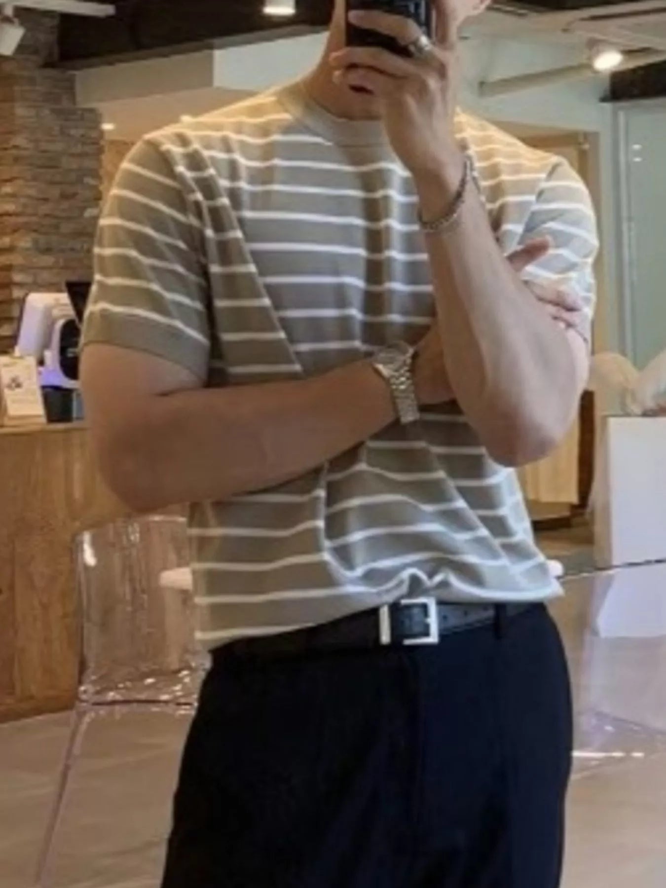 Person wearing a striped shirt and dark pants in an indoor setting