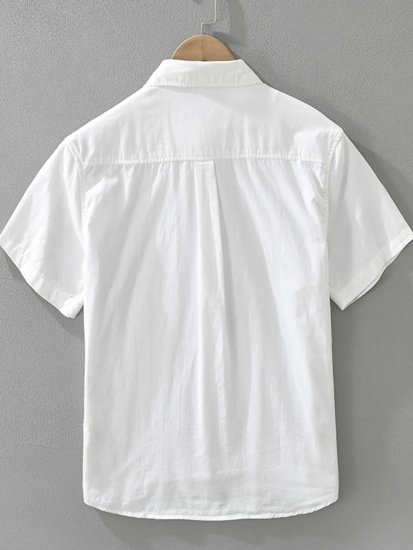 White short-sleeve shirt on a hanger against a gray background
