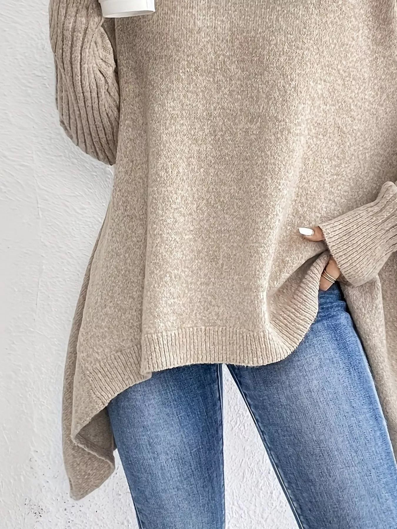 Beige sweater and blue jeans against a white background
