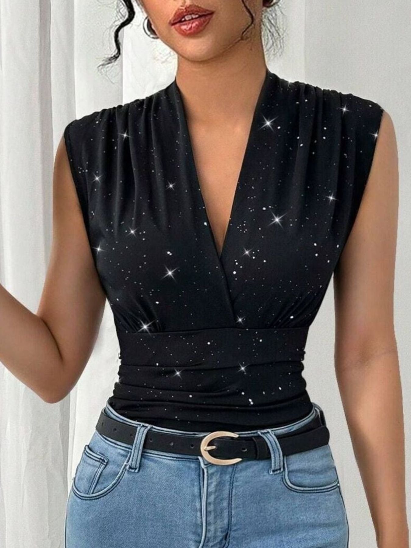 Black star-patterned top worn by a person with blue jeans against a white background