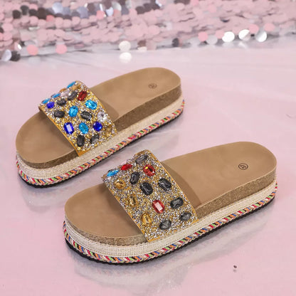 Beige sandals with colorful gemstones on a pink glittery background