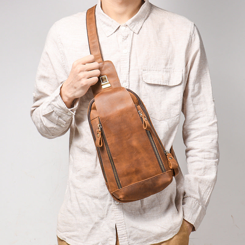 Person wearing a brown leather sling bag against a plain background