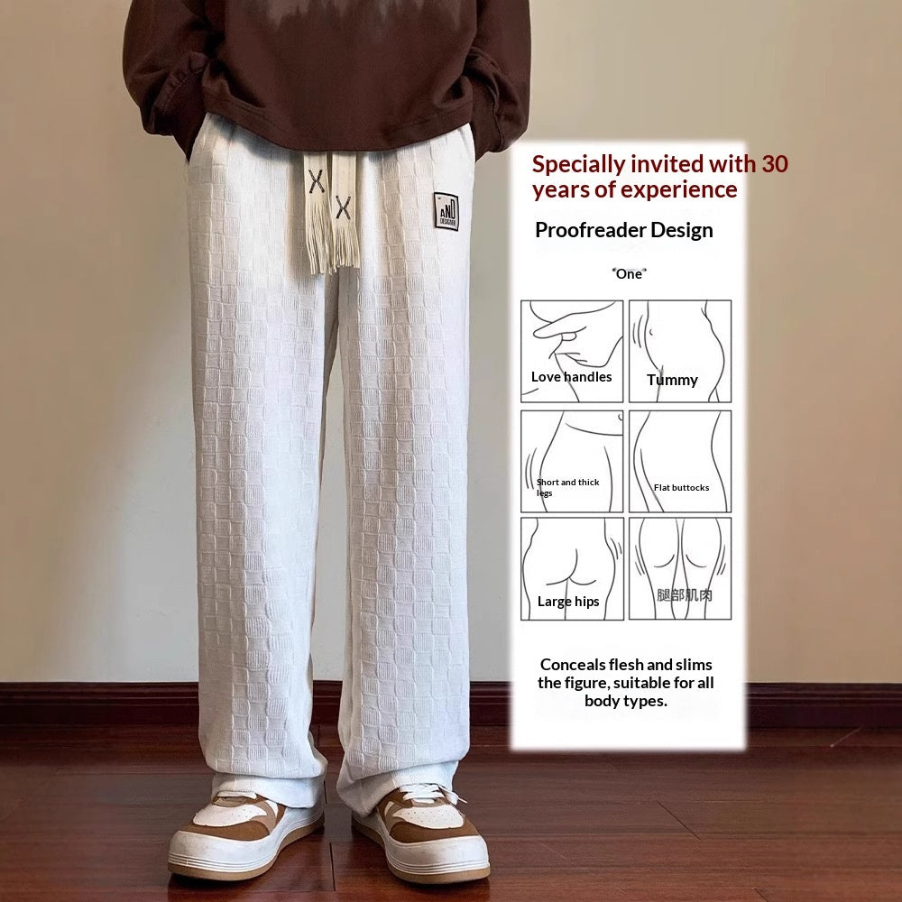 Person wearing white textured pants with a design poster on a beige wall.
