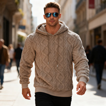 Man wearing a beige cable knit hoodie and sunglasses on a city street.