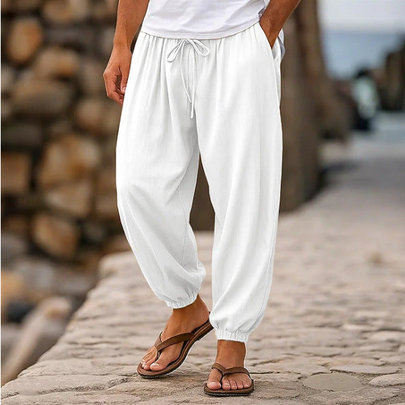 Person wearing white pants and sandals on a stone path with wooden logs in the background