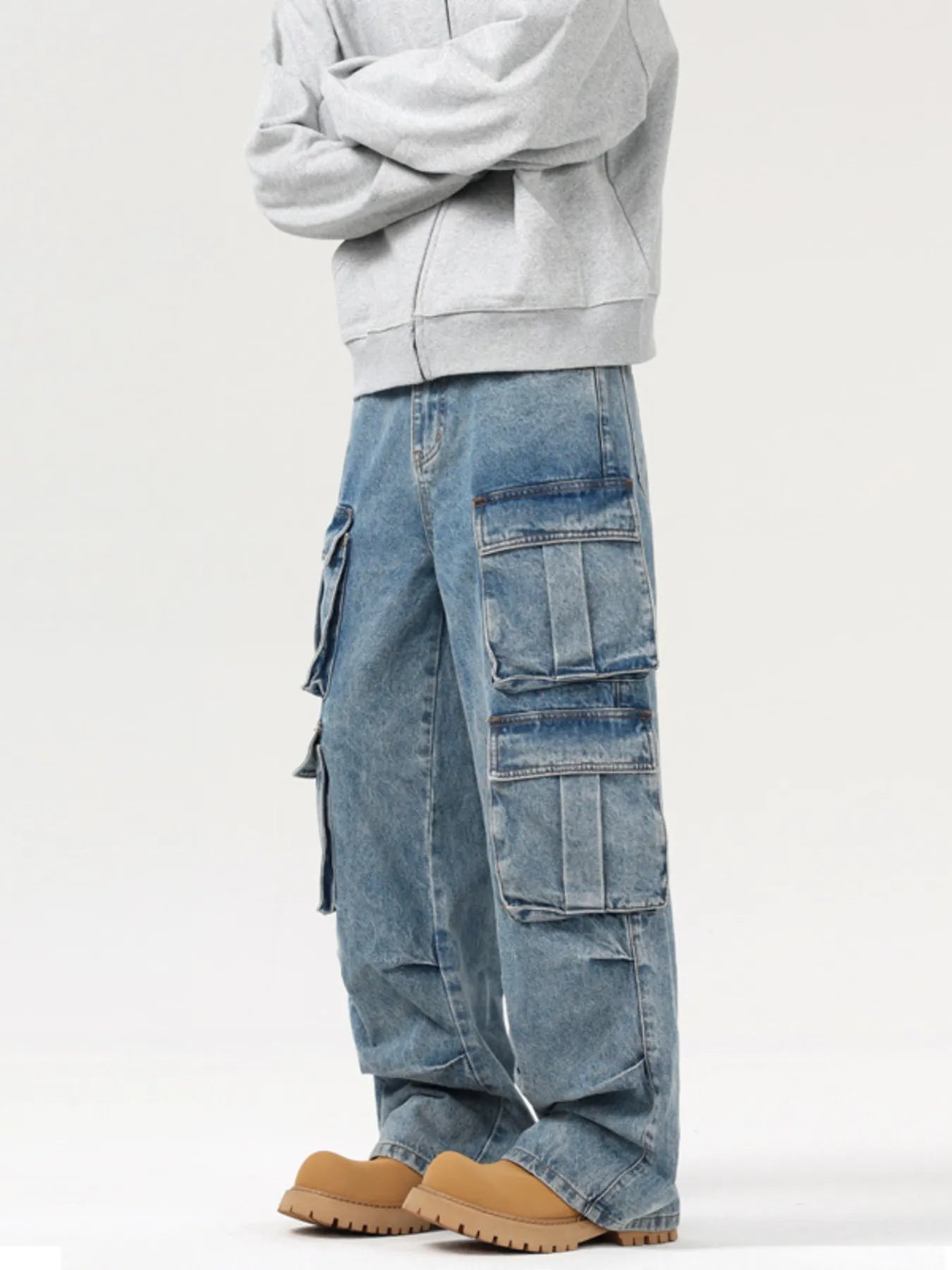 Person wearing a light gray hoodie and blue cargo pants on a white background