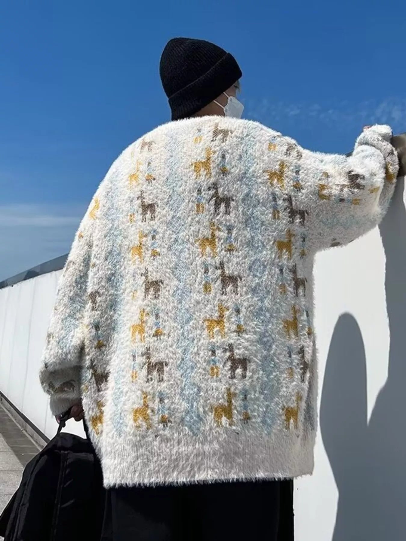 Person wearing a patterned sweater on a bridge with blue sky