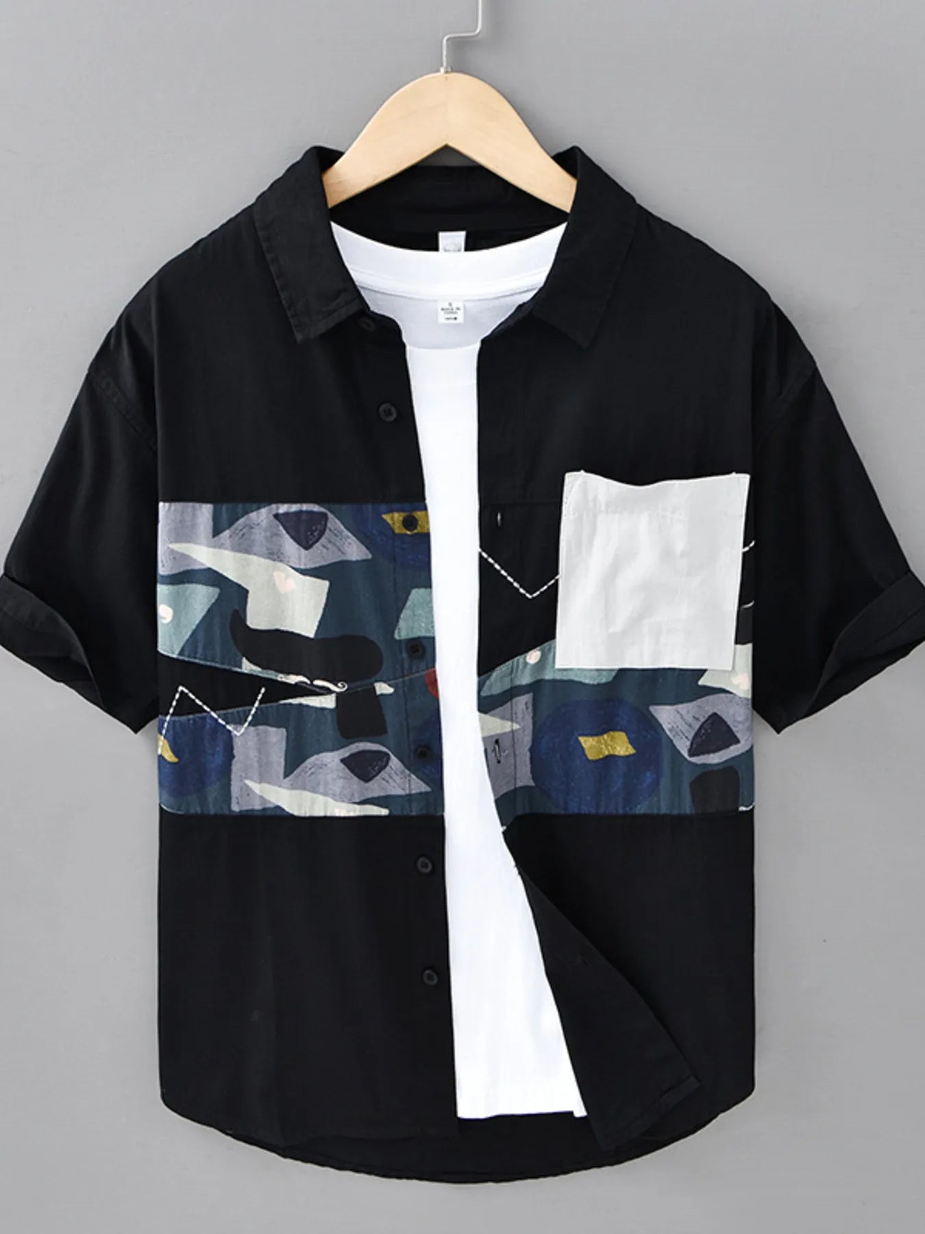 Black and white shirt with abstract pattern on a hanger against a gray background