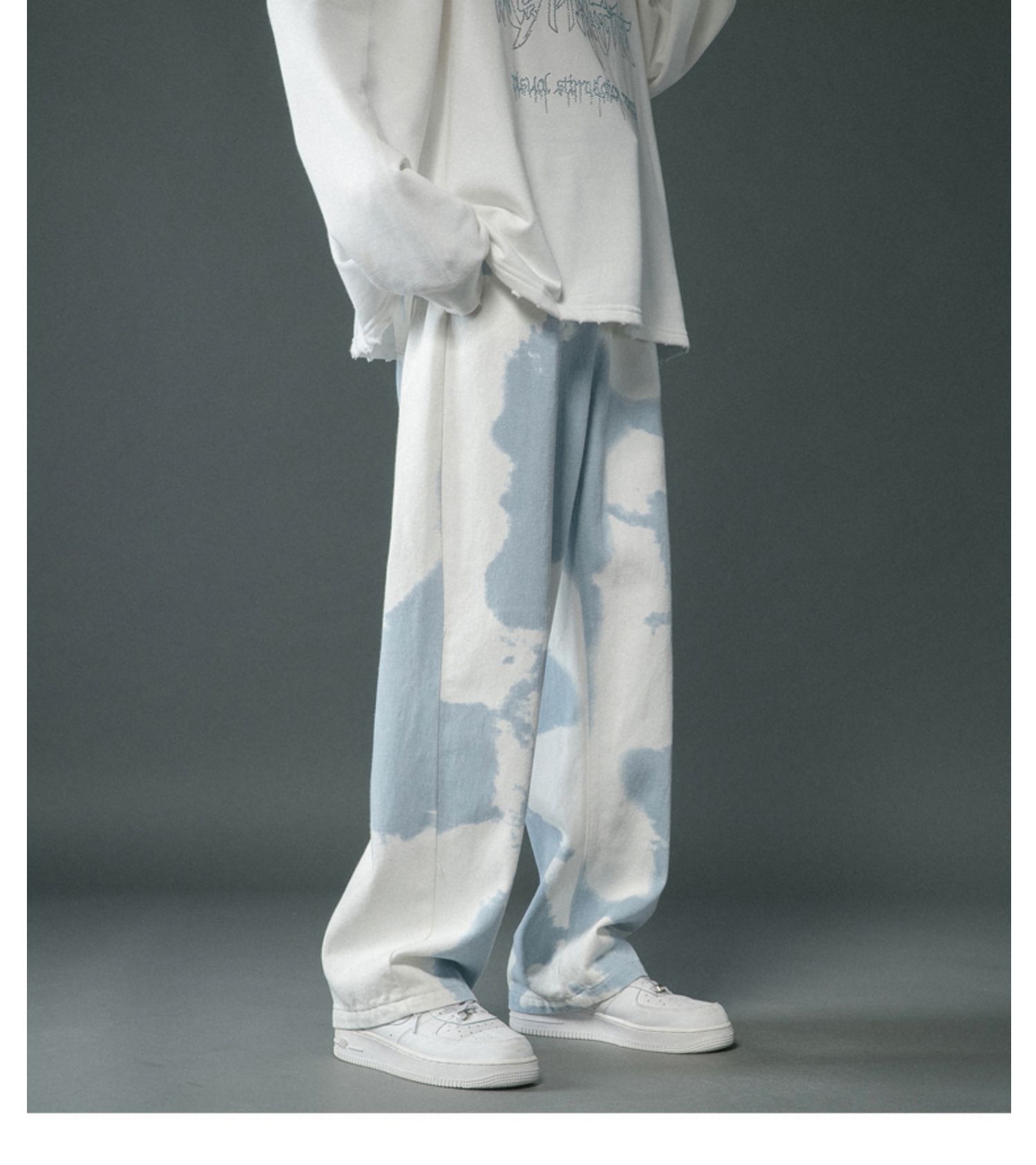 Person wearing a white outfit with blue tie-dye pants on a gray background