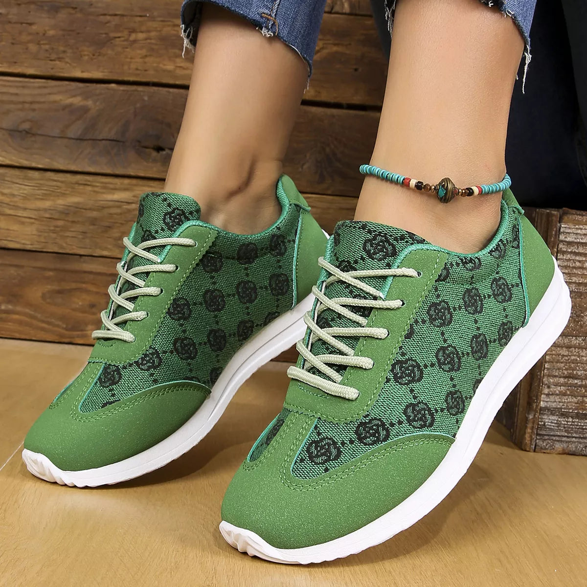 Green sneakers with floral pattern worn by a person on a wooden floor.