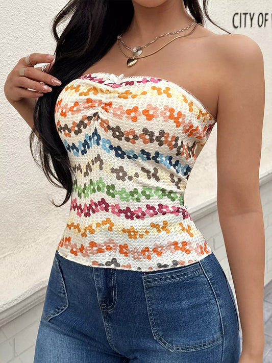 Woman wearing a colorful floral strapless top and blue jeans against a light background.