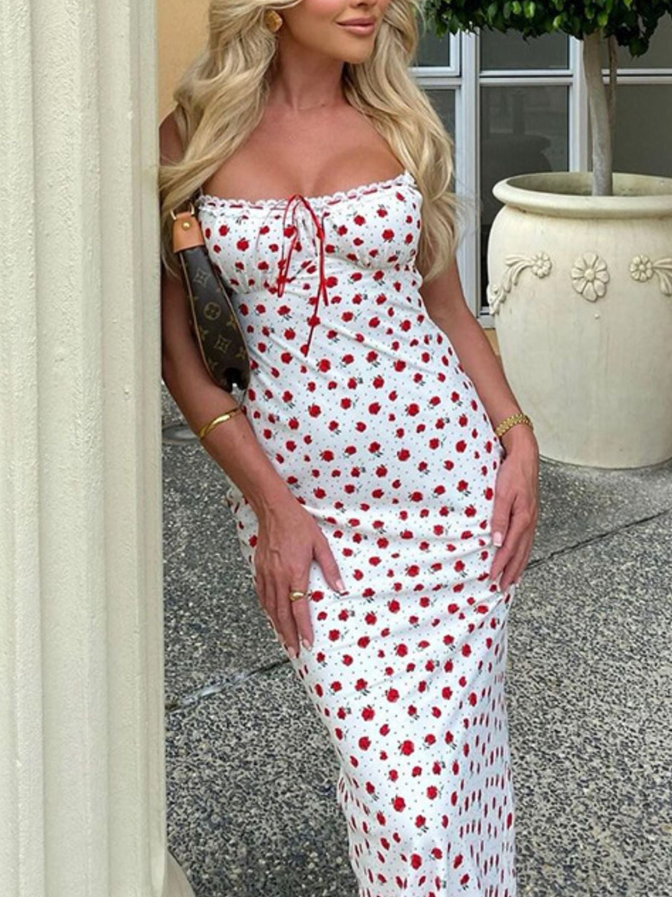 Woman wearing a white dress with red polka dots, standing outdoors.