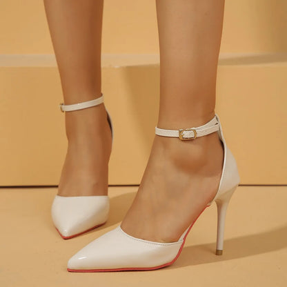 White high-heeled shoes with thin straps on a beige background
