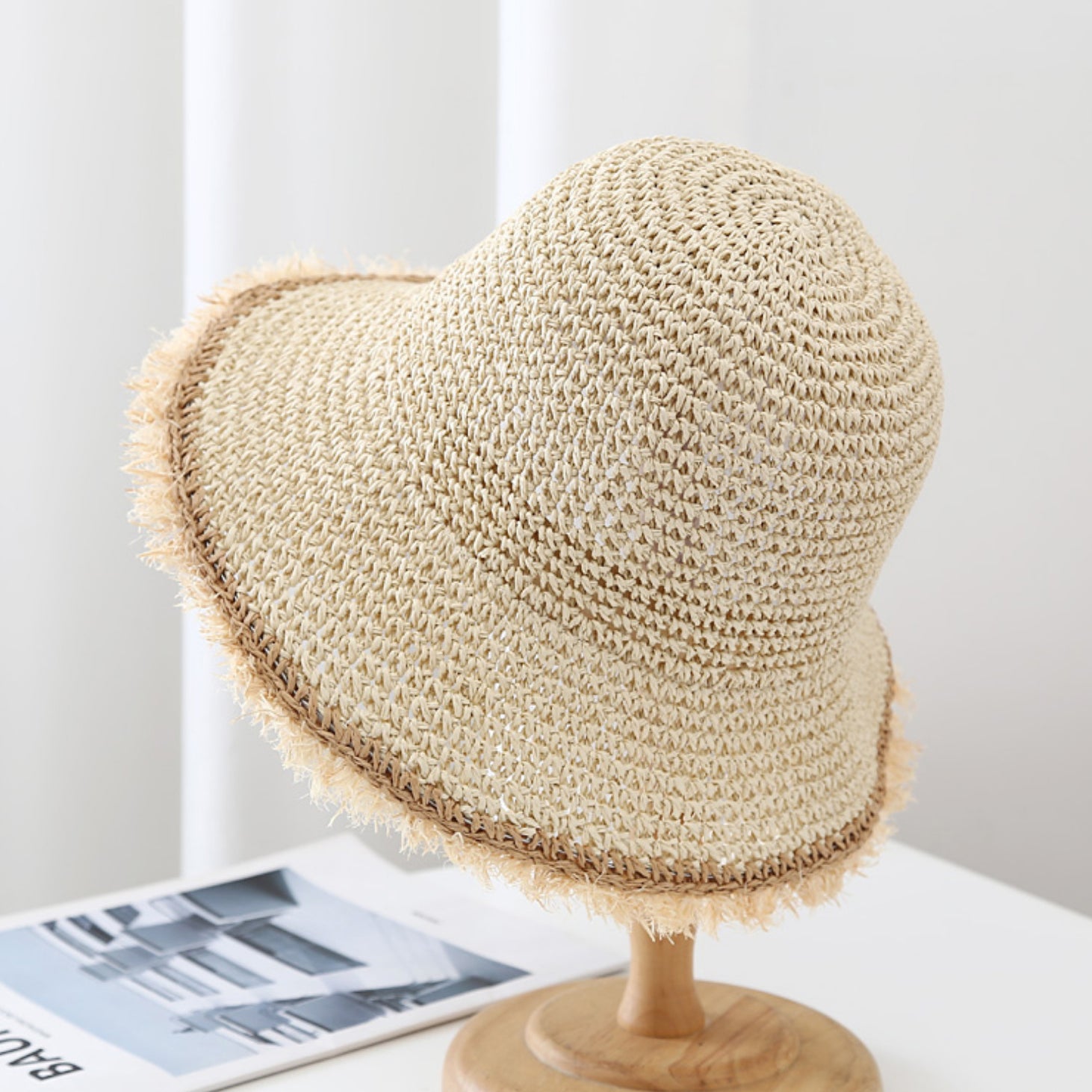 Beige straw hat on a mannequin head against a white background