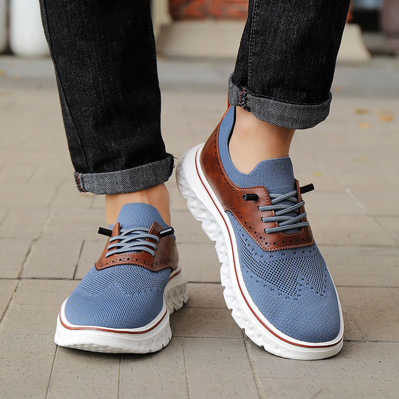 Blue and brown shoes worn with rolled-up jeans on a pavement.