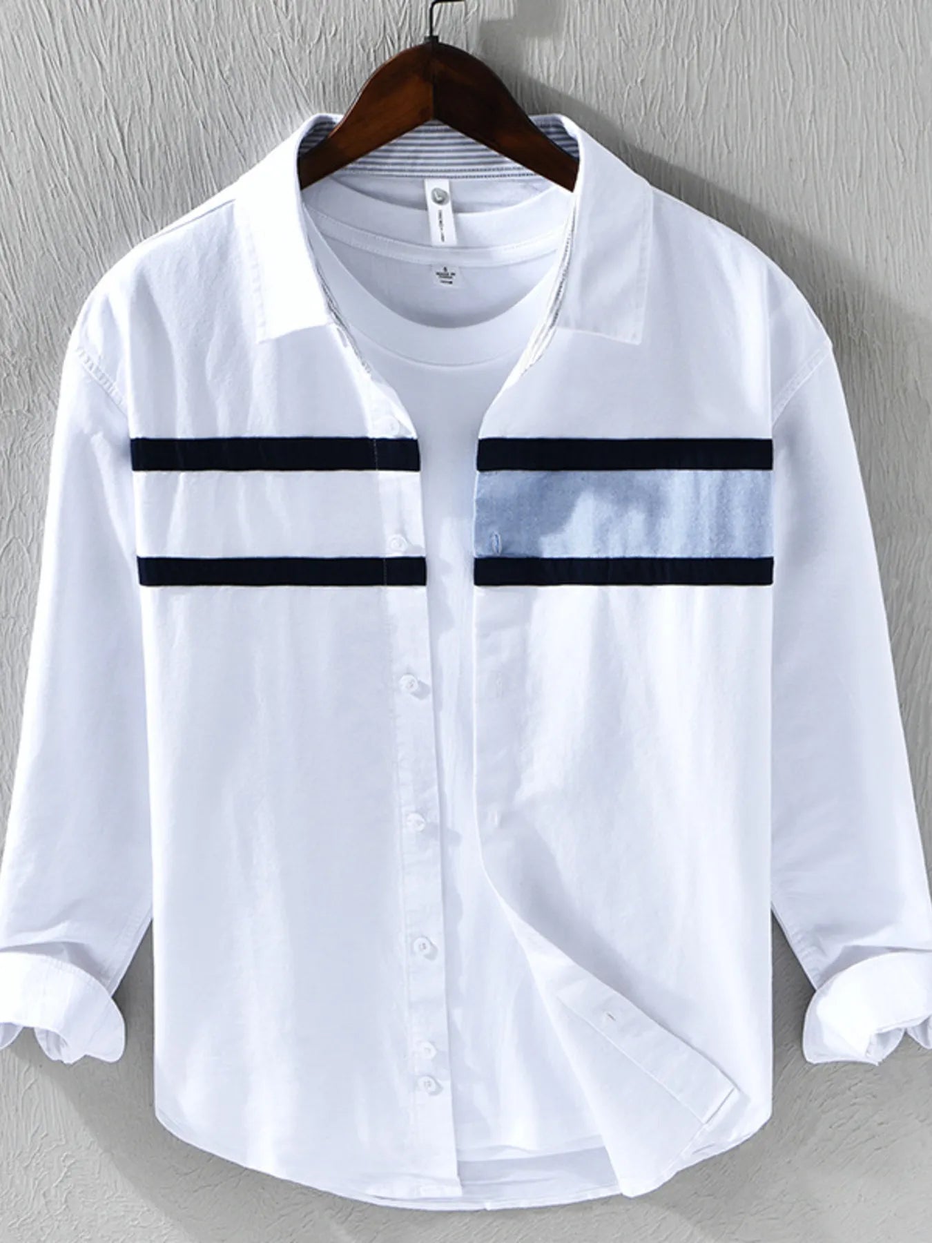 White shirt with black stripes on a hanger against a gray background
