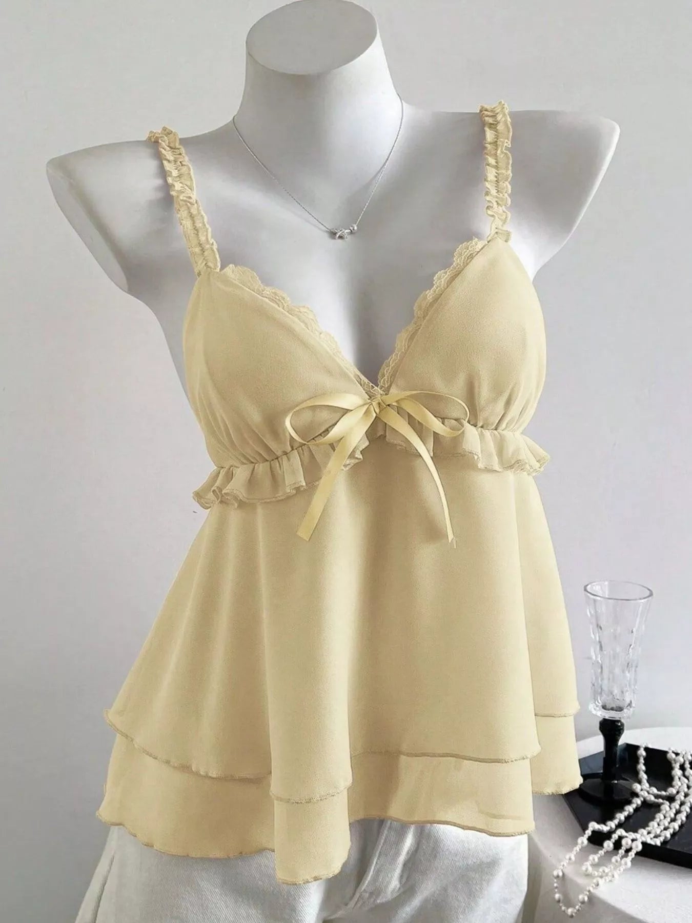 Yellow lace-trimmed nightgown on a mannequin against a plain background