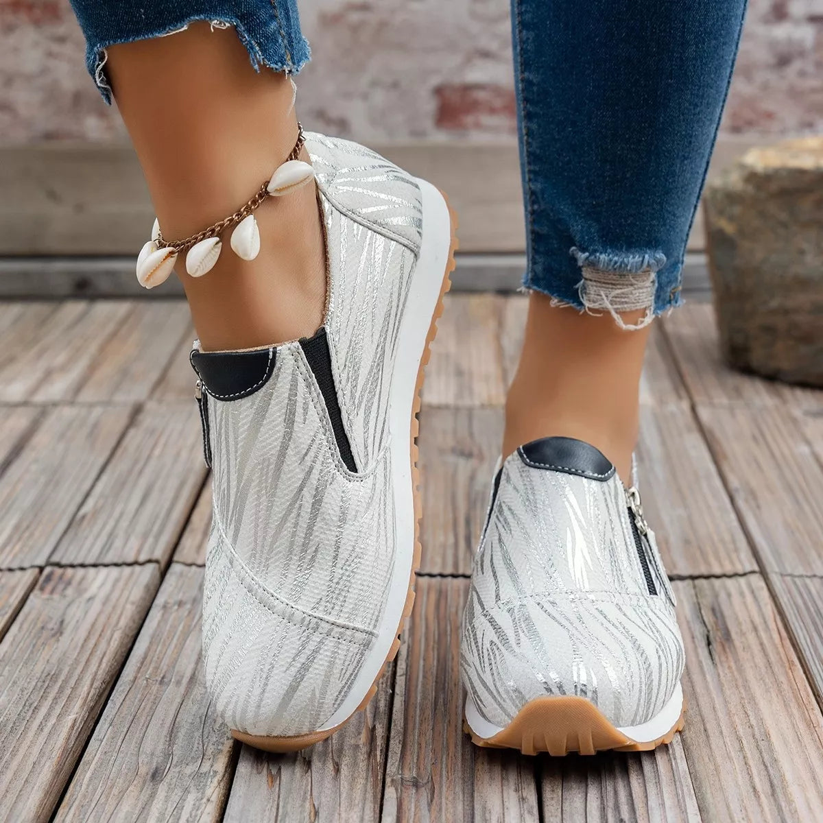 White sneakers with brown soles worn on a wooden floor