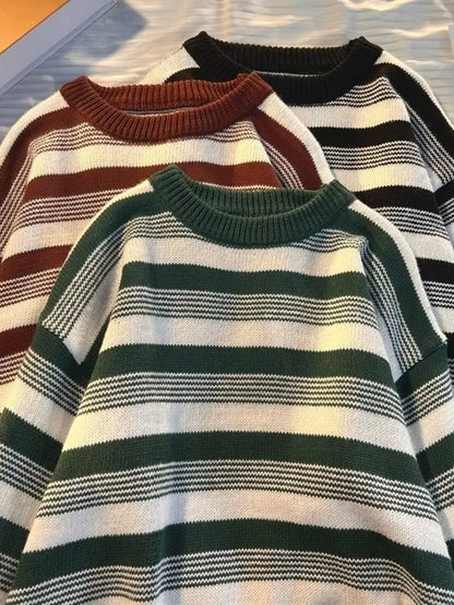 Three striped sweaters in different colors on a textured surface.