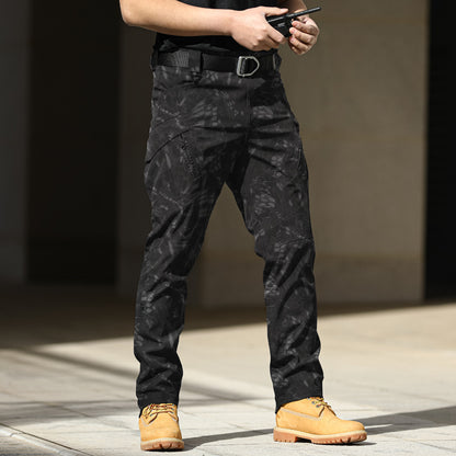 Person wearing black camouflage pants and yellow boots holding a gun.