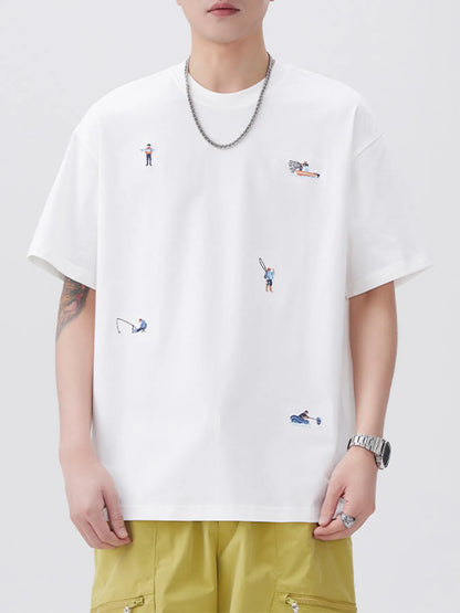 Person wearing a white t-shirt with small embroidered designs on a plain background