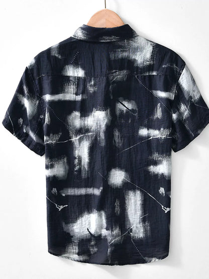 Black and white tie-dye shirt on a hanger against a white background
