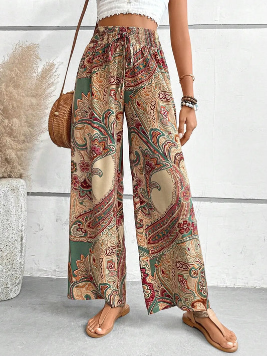 Person wearing patterned wide-leg pants with a white wall and plant in the background