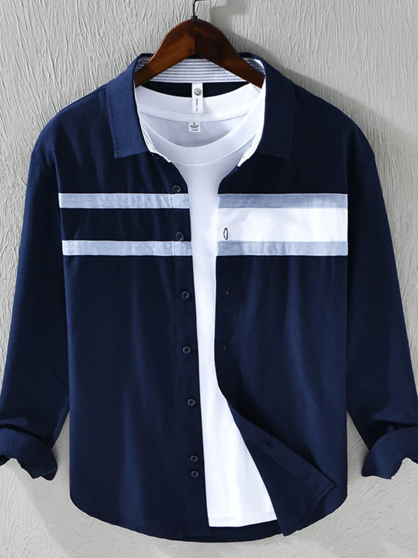Navy blue and white striped shirt on a hanger against a gray background