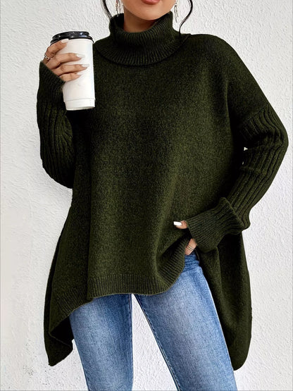 Person wearing a dark green sweater and blue jeans, holding a white cup.