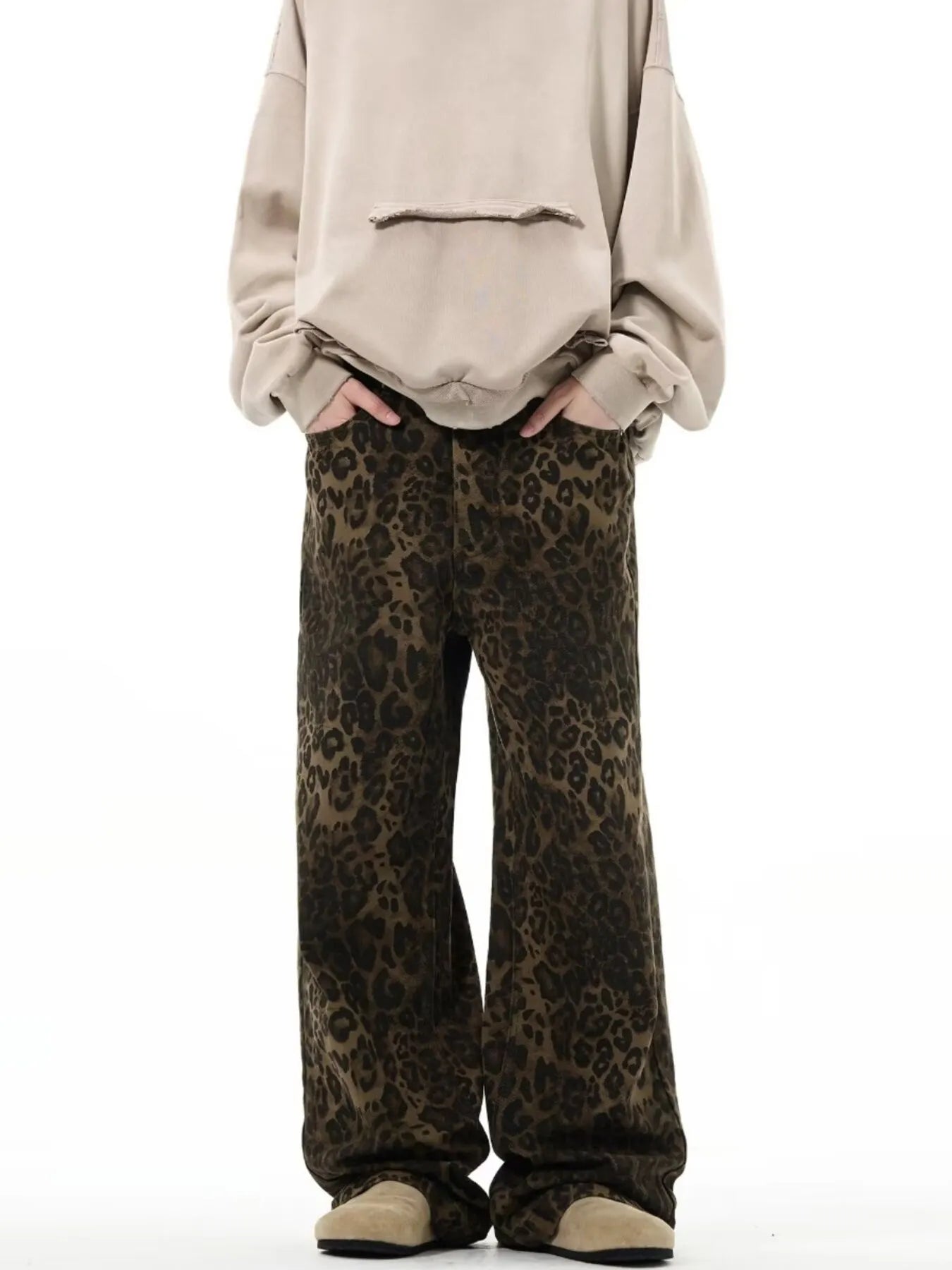 Person wearing leopard print pants and a beige sweatshirt on a white background